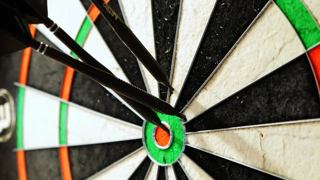 Tre dartpile i bullseye på en dartskive